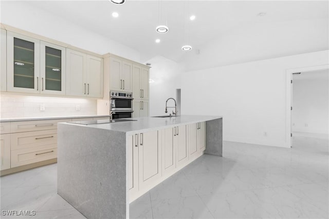 kitchen with marble finish floor, stainless steel double oven, decorative backsplash, and a sink