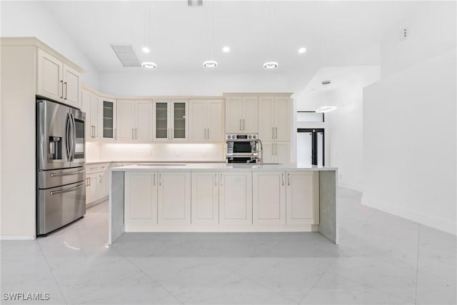 kitchen with marble finish floor, light countertops, appliances with stainless steel finishes, glass insert cabinets, and a kitchen island with sink