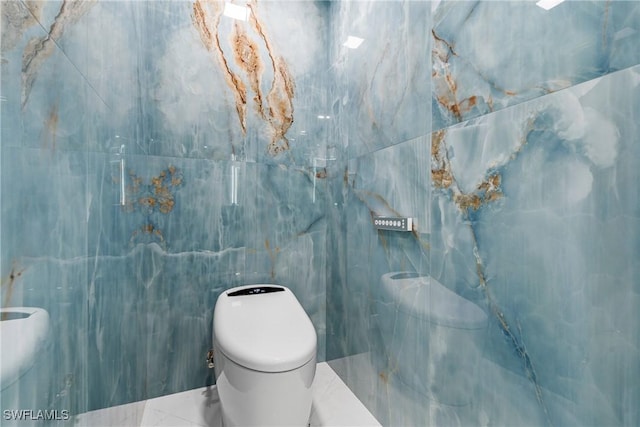 bathroom featuring toilet and tile walls