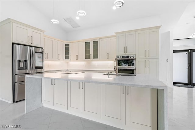 kitchen with stainless steel appliances, marble finish floor, a large island, light countertops, and glass insert cabinets