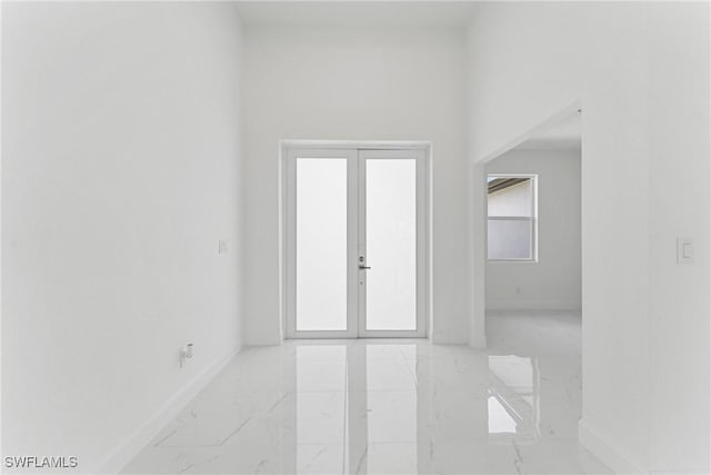 unfurnished room featuring marble finish floor, baseboards, and french doors