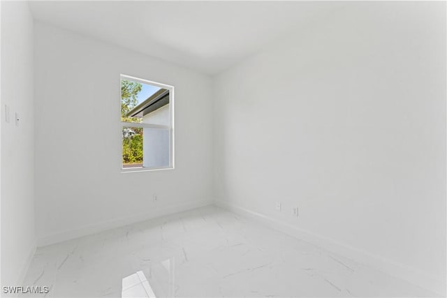 unfurnished room featuring marble finish floor and baseboards