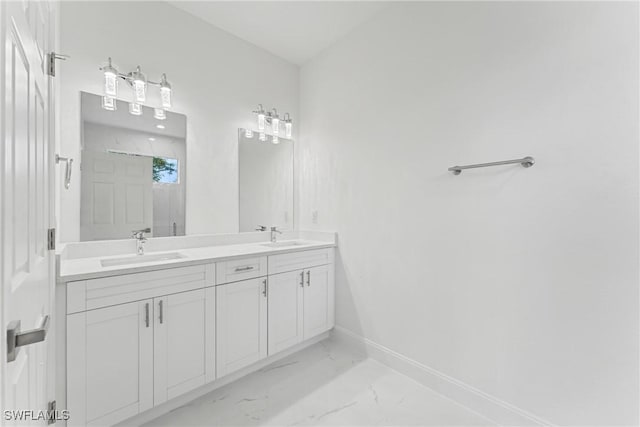 full bath with marble finish floor, double vanity, a sink, and baseboards