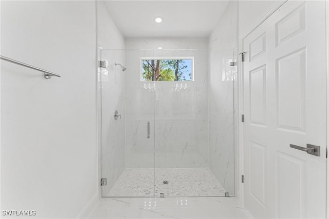 bathroom with a marble finish shower and baseboards