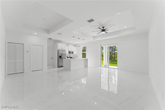 unfurnished living room featuring visible vents, a ceiling fan, marble finish floor, a tray ceiling, and recessed lighting