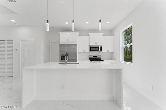 kitchen with white cabinetry, marble finish floor, appliances with stainless steel finishes, light countertops, and a large island with sink