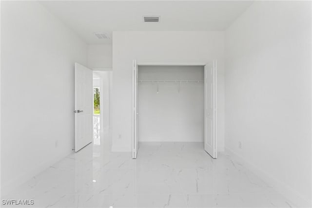 unfurnished bedroom with marble finish floor, a closet, visible vents, and baseboards