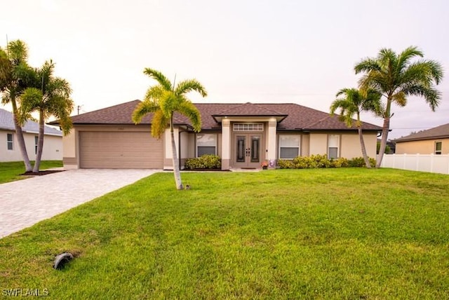 view of front facade featuring decorative driveway, french doors, stucco siding, an attached garage, and a front yard