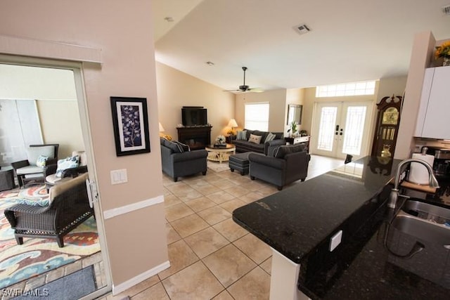 living area featuring french doors, a fireplace, visible vents, light tile patterned flooring, and ceiling fan