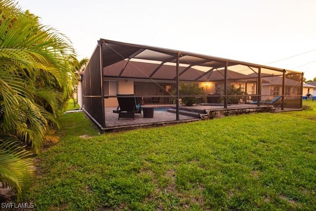 rear view of property with a yard, a patio area, glass enclosure, and an outdoor pool