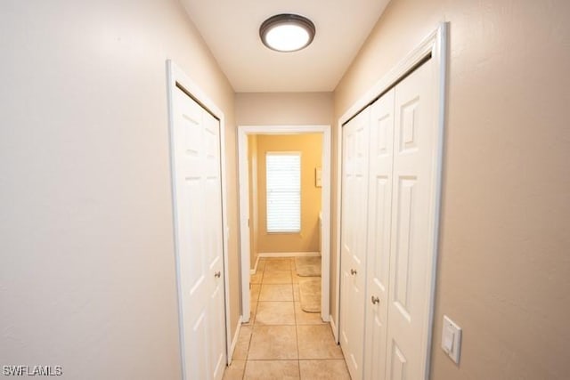 hall with baseboards and light tile patterned flooring