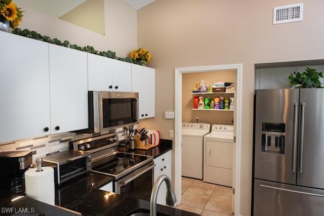 kitchen with visible vents, white cabinets, dark countertops, stainless steel appliances, and washing machine and dryer