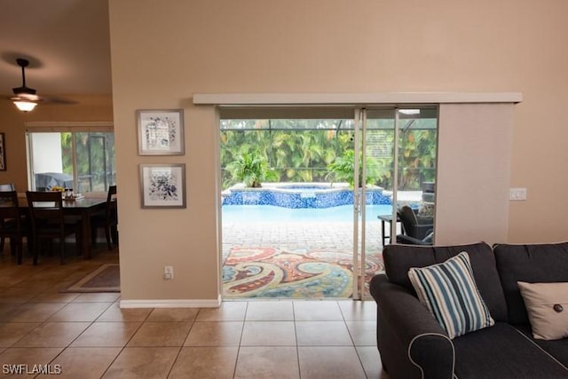 living area with a ceiling fan, baseboards, and tile patterned floors