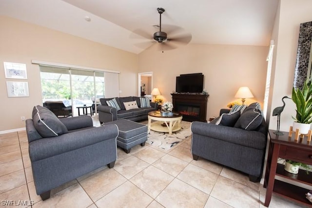 living area featuring a ceiling fan, lofted ceiling, light tile patterned flooring, and a glass covered fireplace