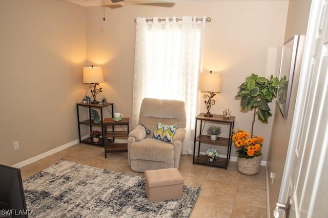 living area featuring tile patterned flooring, baseboards, and ceiling fan