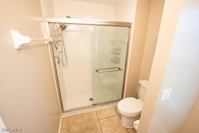 full bathroom with a stall shower, toilet, and tile patterned floors