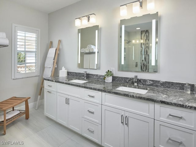 full bath featuring a stall shower, a sink, baseboards, and double vanity