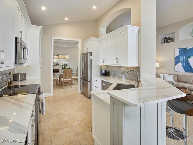 kitchen featuring appliances with stainless steel finishes, white cabinets, a sink, and a peninsula