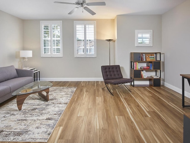 living room with a ceiling fan, baseboards, and wood finished floors