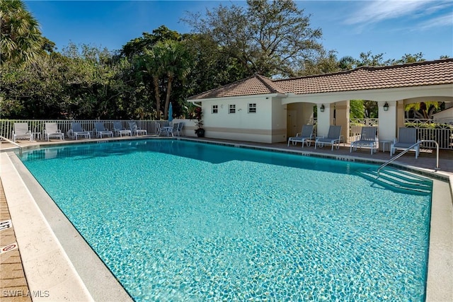 community pool with a patio area and fence