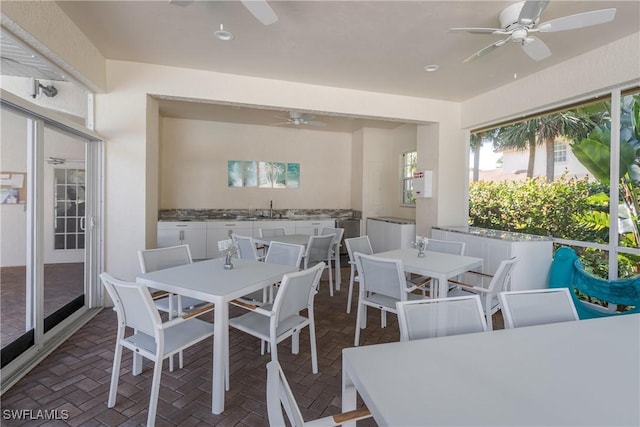 dining room with a ceiling fan and brick floor