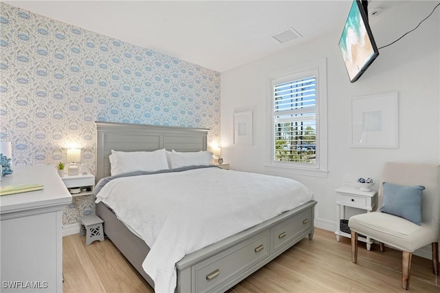 bedroom featuring wallpapered walls, light wood-style flooring, and baseboards