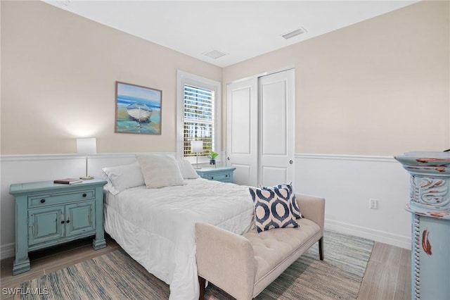 bedroom with baseboards, a closet, visible vents, and wood finished floors