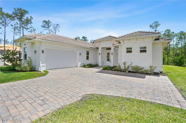 view of front of house featuring a garage, stucco siding, decorative driveway, and a tiled roof