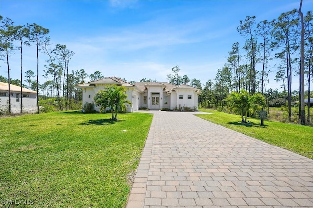 view of front facade featuring decorative driveway, a front lawn, and stucco siding