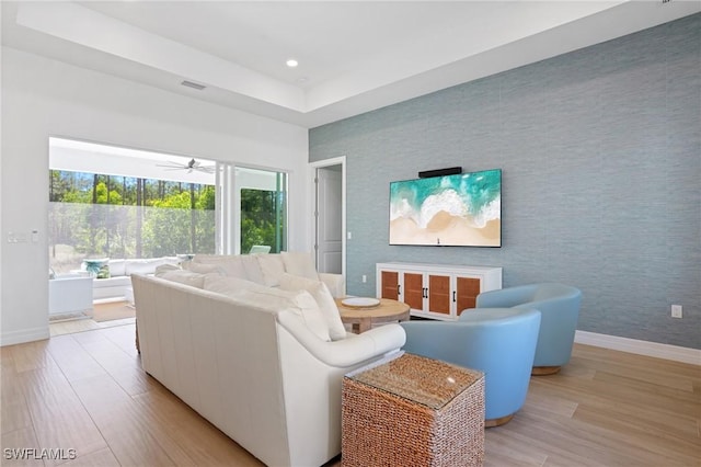 living room with light wood-style flooring, recessed lighting, an accent wall, baseboards, and wallpapered walls