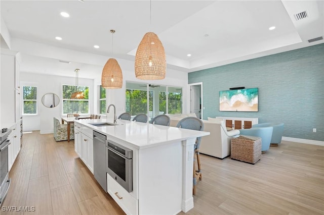 kitchen with wallpapered walls, a raised ceiling, a sink, and stainless steel dishwasher