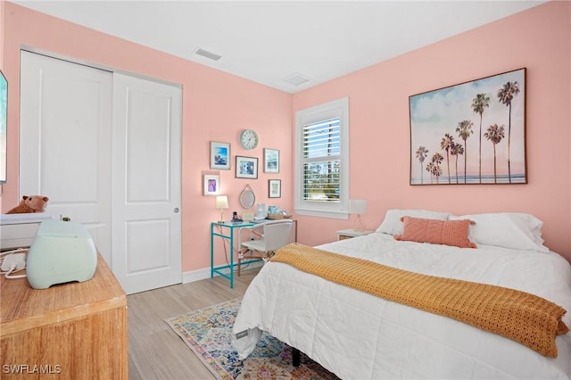 bedroom featuring light wood-style floors, a closet, visible vents, and baseboards