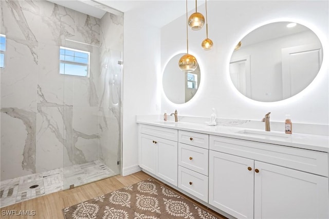 full bath with a sink, a marble finish shower, and double vanity