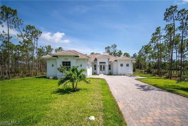 mediterranean / spanish house with a garage, a front lawn, decorative driveway, and stucco siding