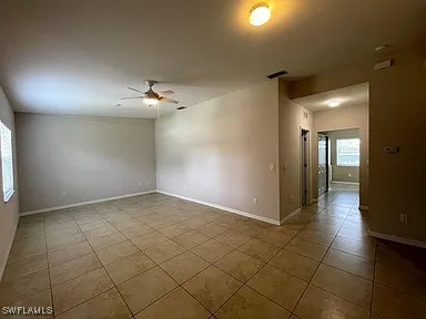 unfurnished room with visible vents, plenty of natural light, baseboards, and ceiling fan