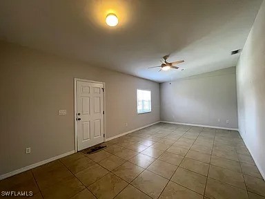 tiled empty room featuring baseboards and ceiling fan