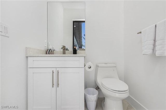 half bath with toilet, vanity, and baseboards