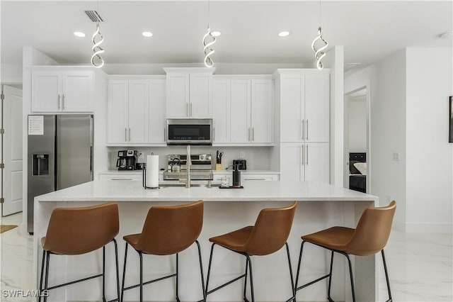 kitchen featuring marble finish floor, a center island with sink, appliances with stainless steel finishes, white cabinets, and light countertops