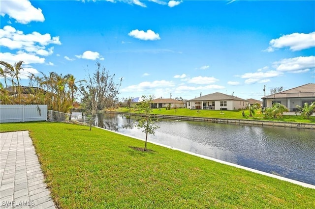 view of yard featuring a residential view, fence, and a water view