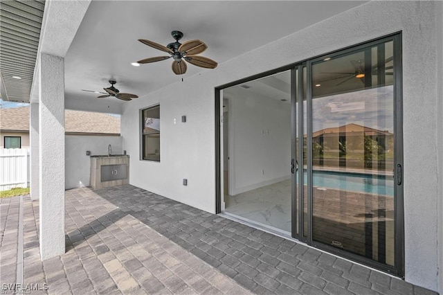 view of patio featuring a sink, fence, and ceiling fan