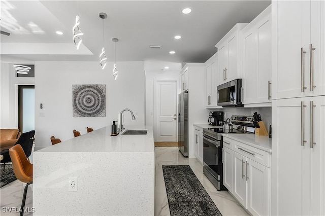 kitchen featuring a sink, marble finish floor, appliances with stainless steel finishes, and a kitchen island with sink