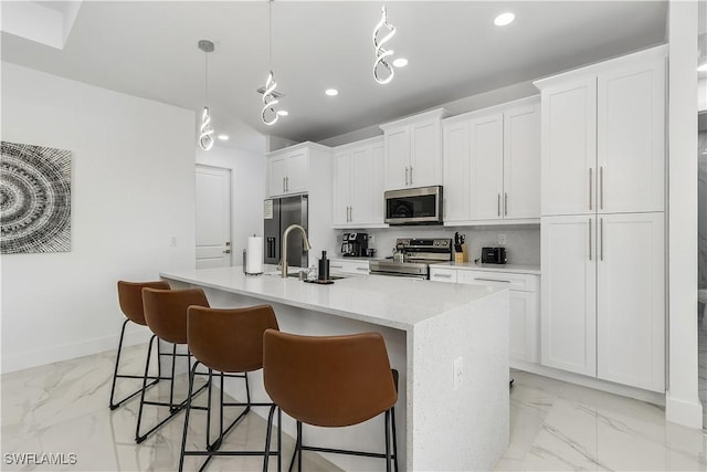 kitchen with a center island with sink, marble finish floor, stainless steel appliances, and a sink