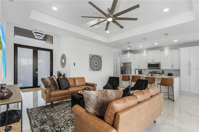 living area featuring recessed lighting, french doors, and a tray ceiling