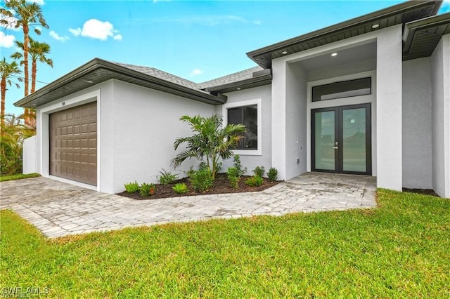 property entrance featuring a yard, stucco siding, french doors, and a garage