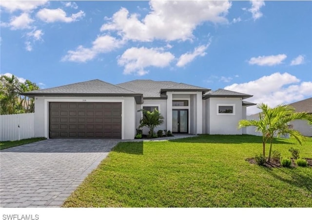 prairie-style home with a front lawn, decorative driveway, fence, french doors, and an attached garage