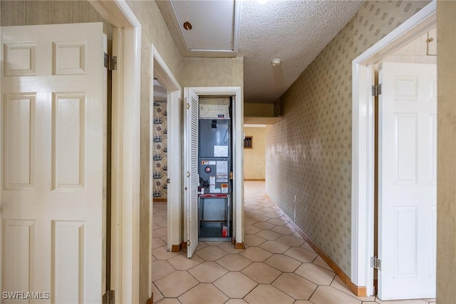 hallway featuring a textured ceiling and wallpapered walls