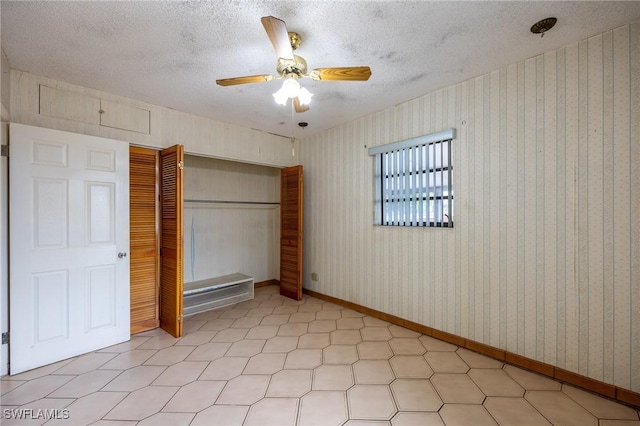 unfurnished bedroom featuring wallpapered walls, baseboards, a ceiling fan, a textured ceiling, and a closet