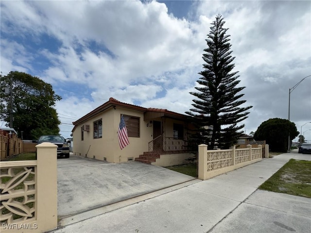 view of front facade featuring a tiled roof, a fenced front yard, and stucco siding