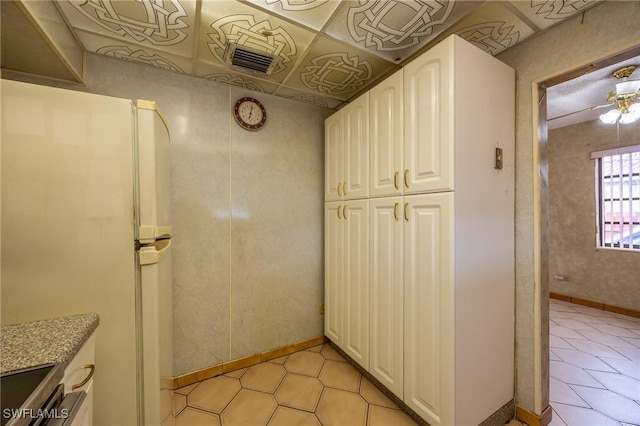 interior space with baseboards, visible vents, white cabinets, stove, and freestanding refrigerator