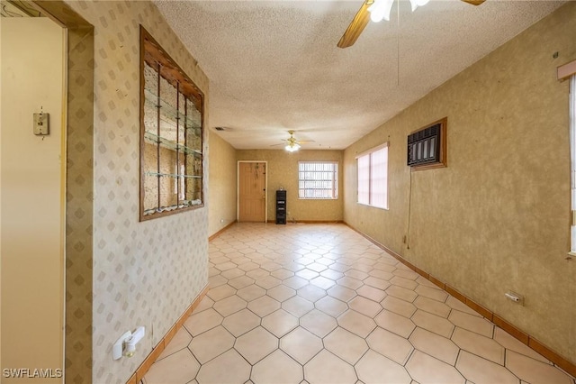 spare room with ceiling fan, a textured ceiling, baseboards, and wallpapered walls